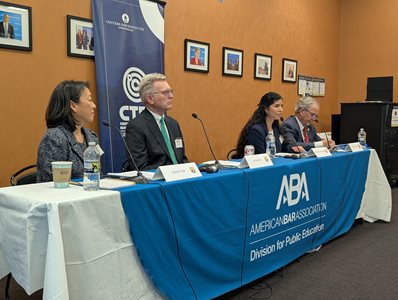  Four panelists seated at a table draped with an American Bar Association Division for Public Education banner during a Law Day panel discussion at Georgetown Law.