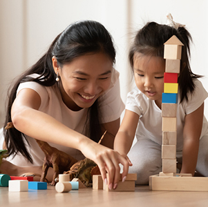 Mother and young daughter playing and building with small wooden blocks