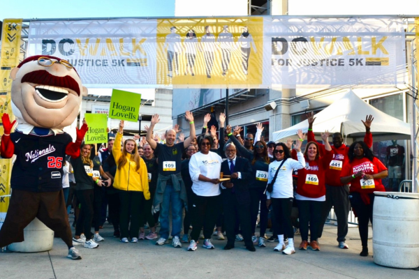 Crowd cheering in front of signs for DC Bar Foundation Walk for Justice